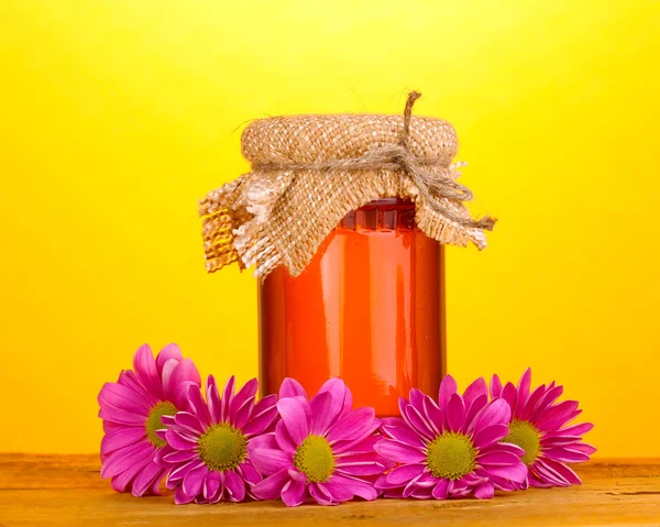 Süßer Honig im Glas auf Holztisch auf gelbem Hintergrund — Stockfoto
