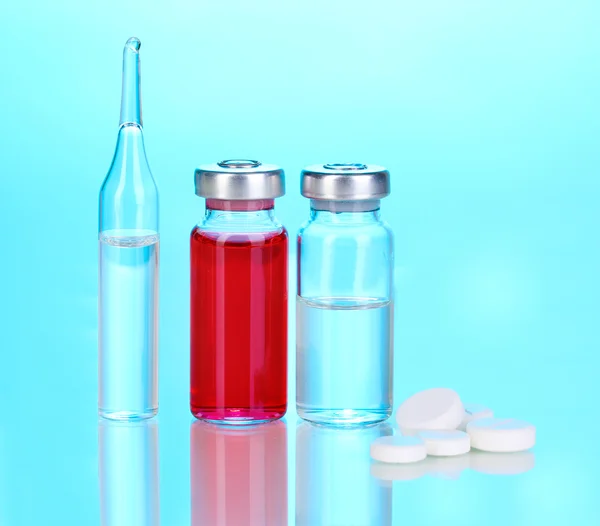 Tabletten und Ampullen auf blauem Hintergrund — Stockfoto