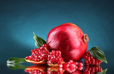 Ripe pomegranate fruit with leaves on blue background clipart