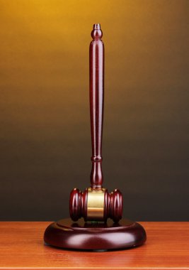 Judge's gavel on wooden table on brown background clipart