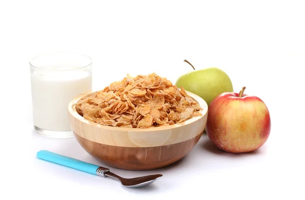 Smaczne płatki kukurydziane w drewniane miski, jabłka i szklankę mleka na białym tle — Zdjęcie stockowe