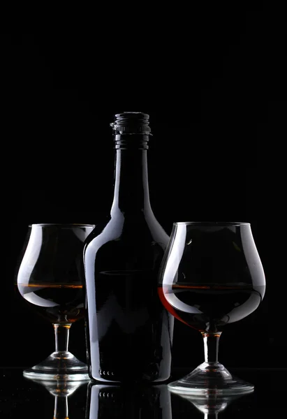 Стаканы бренди и бутылки на черном фоне — стоковое фото