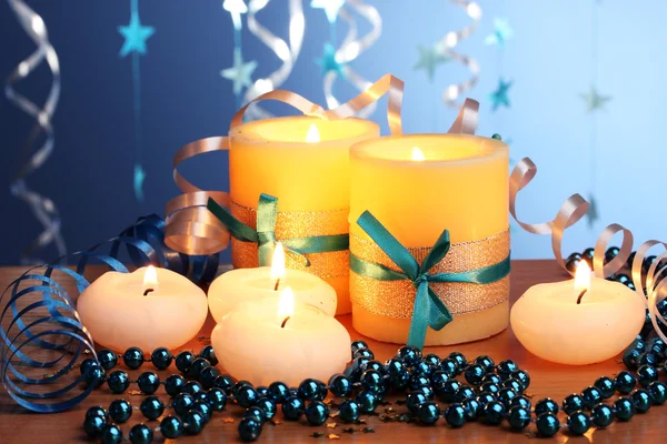 Hermosas velas, regalos y decoración en mesa de madera sobre fondo azul —  Fotos de Stock