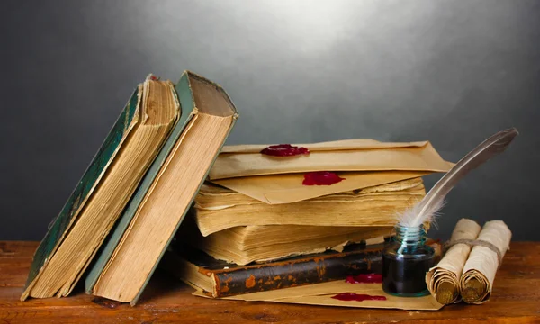 Libri antichi, pergamene, penna piuma e calamaio su tavolo in legno su fondo grigio — Foto Stock