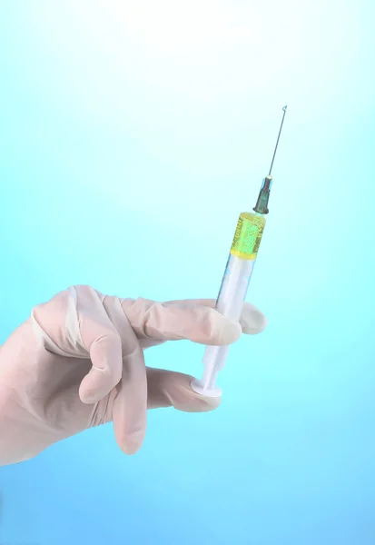 Syringe in hand on blue background — Stock Photo, Image
