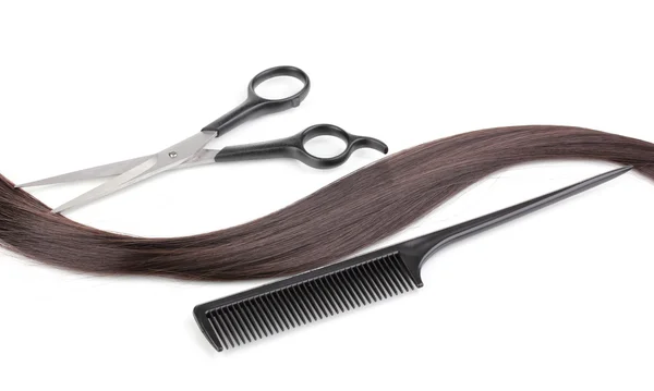 Cabello castaño brillante con tijeras de corte de pelo y peine aislado en blanco —  Fotos de Stock