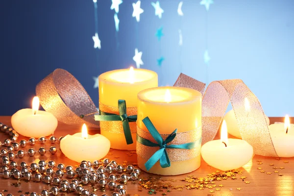 Beautiful candles, gifts and decor on wooden table on blue background Royalty Free Stock Images