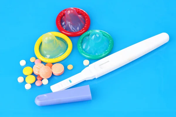 Geburtskondome, Schwangerschaftstest und Antibabypillen auf blauem Hintergrund — Stockfoto
