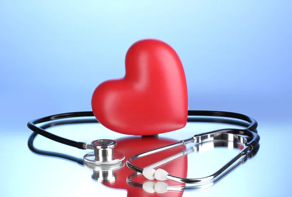 Orvosi sztetoszkóppal, és a szív a kék háttér — Stock Fotó