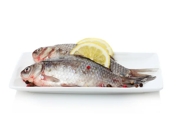 Φρέσκα ψάρια με λεμόνι και πιπέρι στο πιάτο που απομονώνονται σε λευκό — Φωτογραφία Αρχείου
