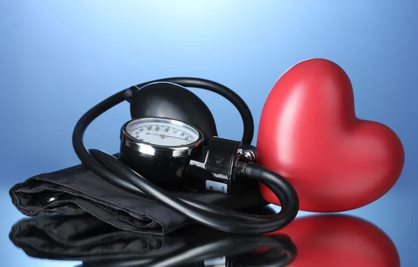 Black tonometer and heart on blue background — Stock Photo, Image