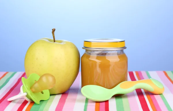 Glas Babypüree mit Löffel auf Serviette auf blauem Hintergrund — Stockfoto