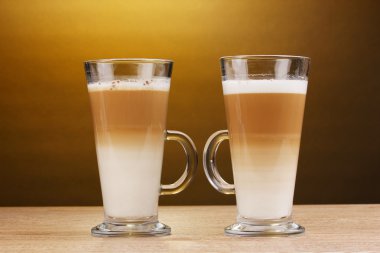 Fragrant сoffee latte in glass cups on wooden table on brown background clipart