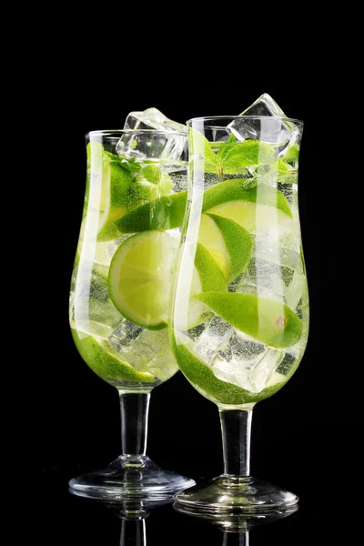 Glazen van cocktails met limoen en munt op zwarte achtergrond — Stockfoto