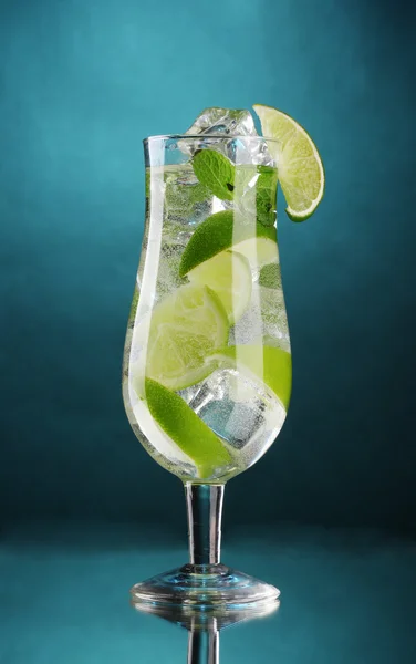 Verre de cocktail avec citron vert et menthe sur fond bleu — Photo