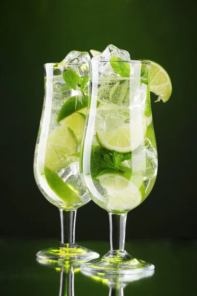 Cocktailgläser mit Limette und Minze auf grünem Hintergrund — Stockfoto