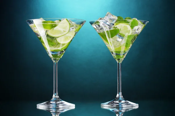 Bicchieri di cocktail con lime e menta su sfondo blu — Foto Stock