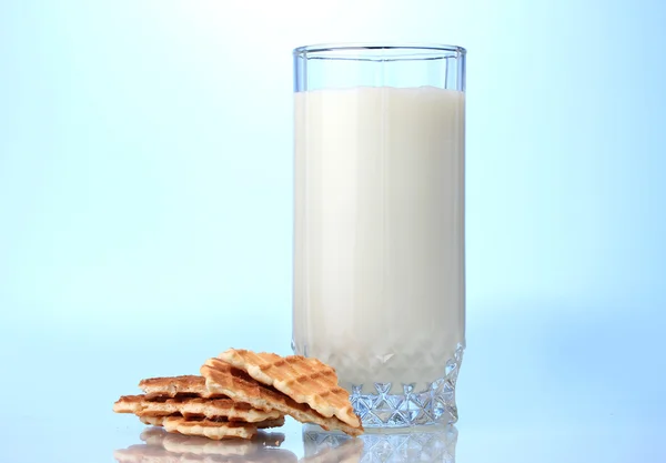 Verre de lait et biscuits sur fond bleu — Photo