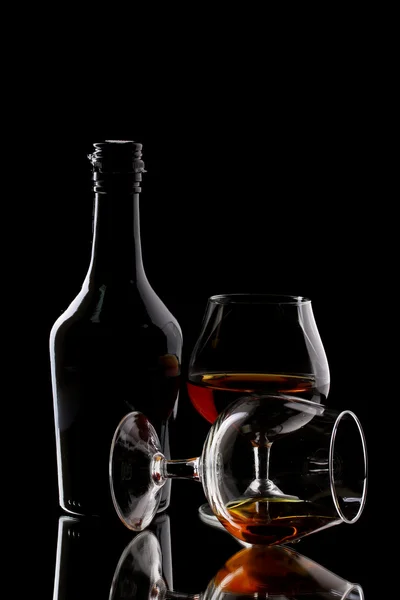 Ποτήρια μπράντυ και μπουκάλι σε μαύρο φόντο — Φωτογραφία Αρχείου