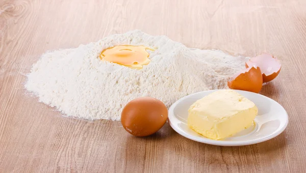 Αυγό, σε αλεύρι και το βούτυρο στο πιάτο στο τραπέζι ξύλινο — Φωτογραφία Αρχείου