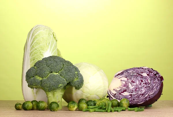Fresh broccoli and cabbages on wooden table on green background — Stock Photo, Image