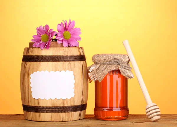 stock image Sweet honey in jar and barrel with drizzler on wooden table on yellow background