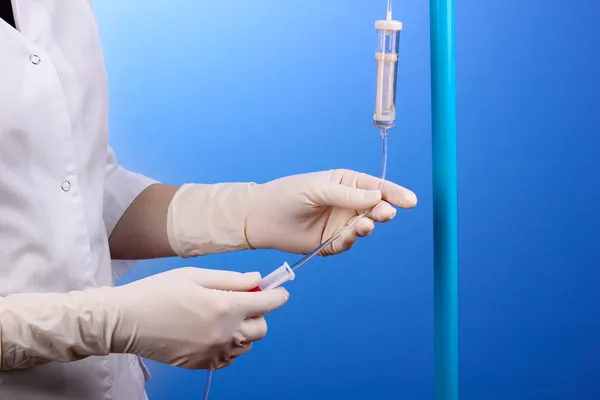 Nurse doing infusion on blue background — Stock Photo, Image