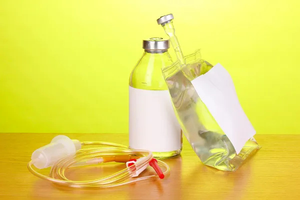 Botella y bolsa de antibióticos intravenosos y juego de infusión de plástico sobre mesa de madera sobre fondo verde — Foto de Stock