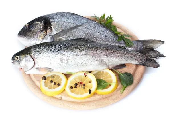 Pesci freschi con limone, prezzemolo e spezie su tagliere di legno isolato su bianco — Foto Stock