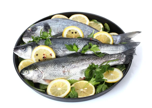 Pesci freschi con limone, prezzemolo e pepe su piatto isolato su bianco — Foto Stock