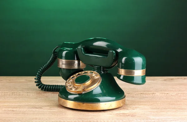 Ретро телефон на деревянном столе на зеленом фоне — стоковое фото