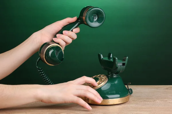 Uppringning på retro telefon på träbord på grön bakgrund — Stockfoto
