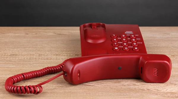 Red phone on wooden table on grey background — Stock Photo, Image