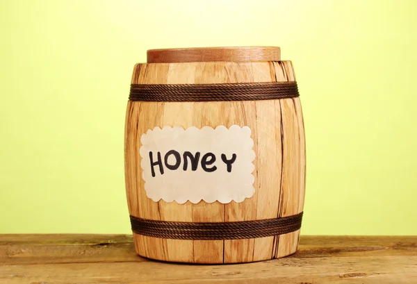 Сладкий мед в бочке с капельницей на деревянном столе на зеленом фоне — стоковое фото