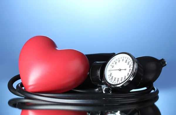 Schwarzes Tonometer und Herz auf blauem Hintergrund — Stockfoto