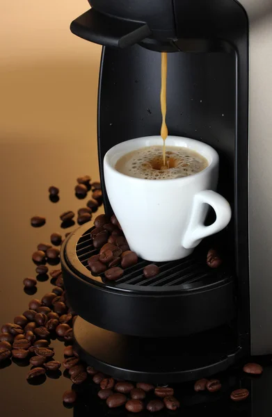 Máquina de café expresso derramando café na xícara no fundo marrom — Fotografia de Stock