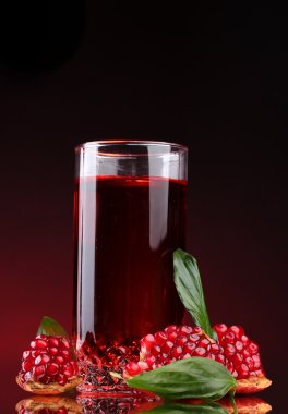 Ripe pomergranate and glass of juice on red background clipart