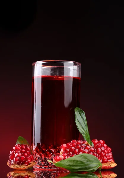 Pomergranato maduro y vaso de jugo sobre fondo rojo — Foto de Stock