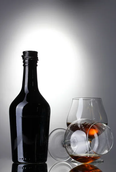 Glas konjak och flaska på grå bakgrund — Stockfoto