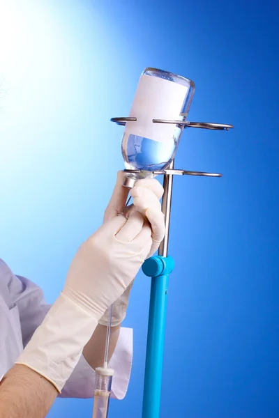 Enfermeira fazendo infusão em fundo azul — Fotografia de Stock
