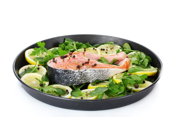 Pesce rosso con limone, prezzemolo e pepe su piatto isolato su bianco — Foto Stock