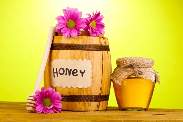 Sweet honey in barrel and jar with drizzler on wooden table on green background — Stock Photo, Image