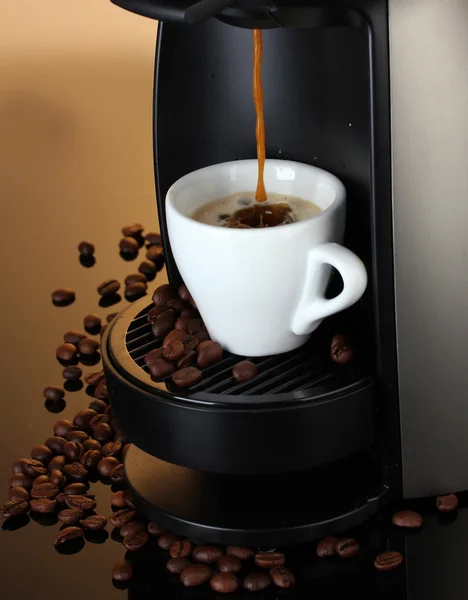 Máquina de café expreso vertiendo café en taza sobre fondo marrón —  Fotos de Stock
