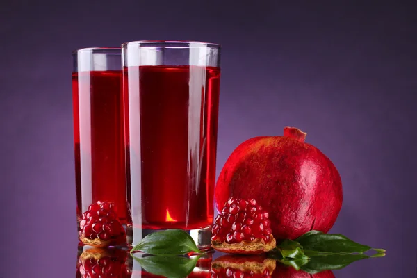 stock image Ripe pomergranate and glasses of juice on purple background