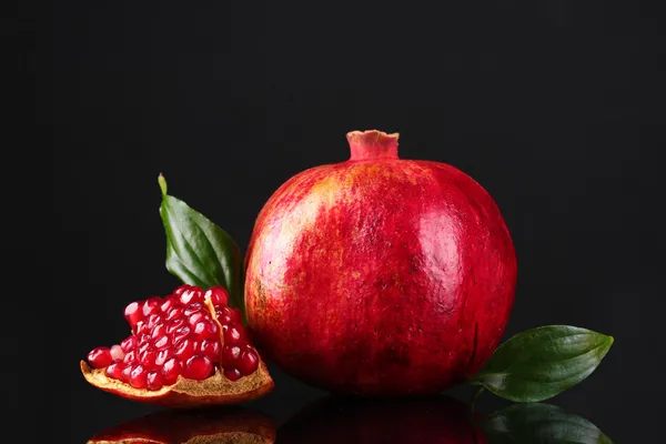 Rijp granaatappel fruit met verlaat op zwarte achtergrond — Stockfoto