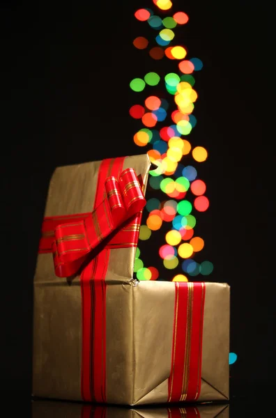 Open golden gift box with bokeh background on black — Stock Photo, Image
