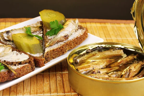 갈색 배경에 나무 매트에 접시에 sprats와 맛 있는 샌드위치 — 스톡 사진