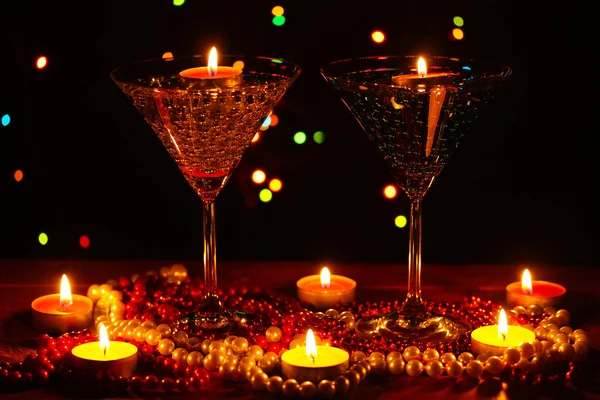 Composição surpreendente de velas e óculos na mesa de madeira no fundo brilhante — Fotografia de Stock