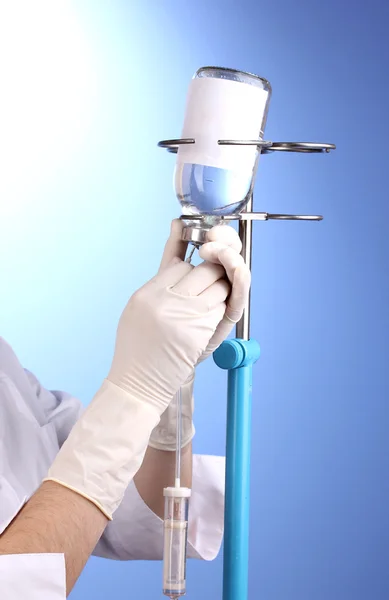 Sjuksköterska gör infusion på blå bakgrund — Stockfoto