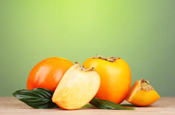 在绿色背景上的木桌上的开胃柿子 — 图库照片